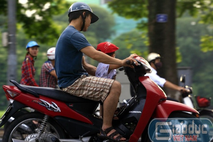 Không cần đai đeo, cũng chẳng cần mũ bảo hiểm cho cháu bé, ông bố này vừa đi trên phố vừa đùa với con rất nguy hiểm